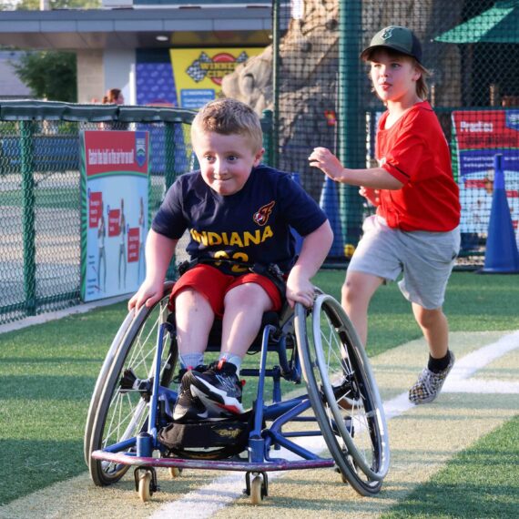 Kid in a wheelchair going around the bases on a baseball diamond.