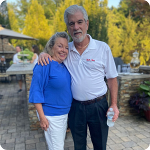 Husband and wife donors smiling with arms around each other.