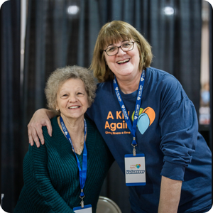 Two volunteers for A Kid Again smiling at an adventure.