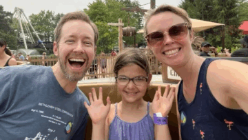 Smiling family on a ride at a theme park.
